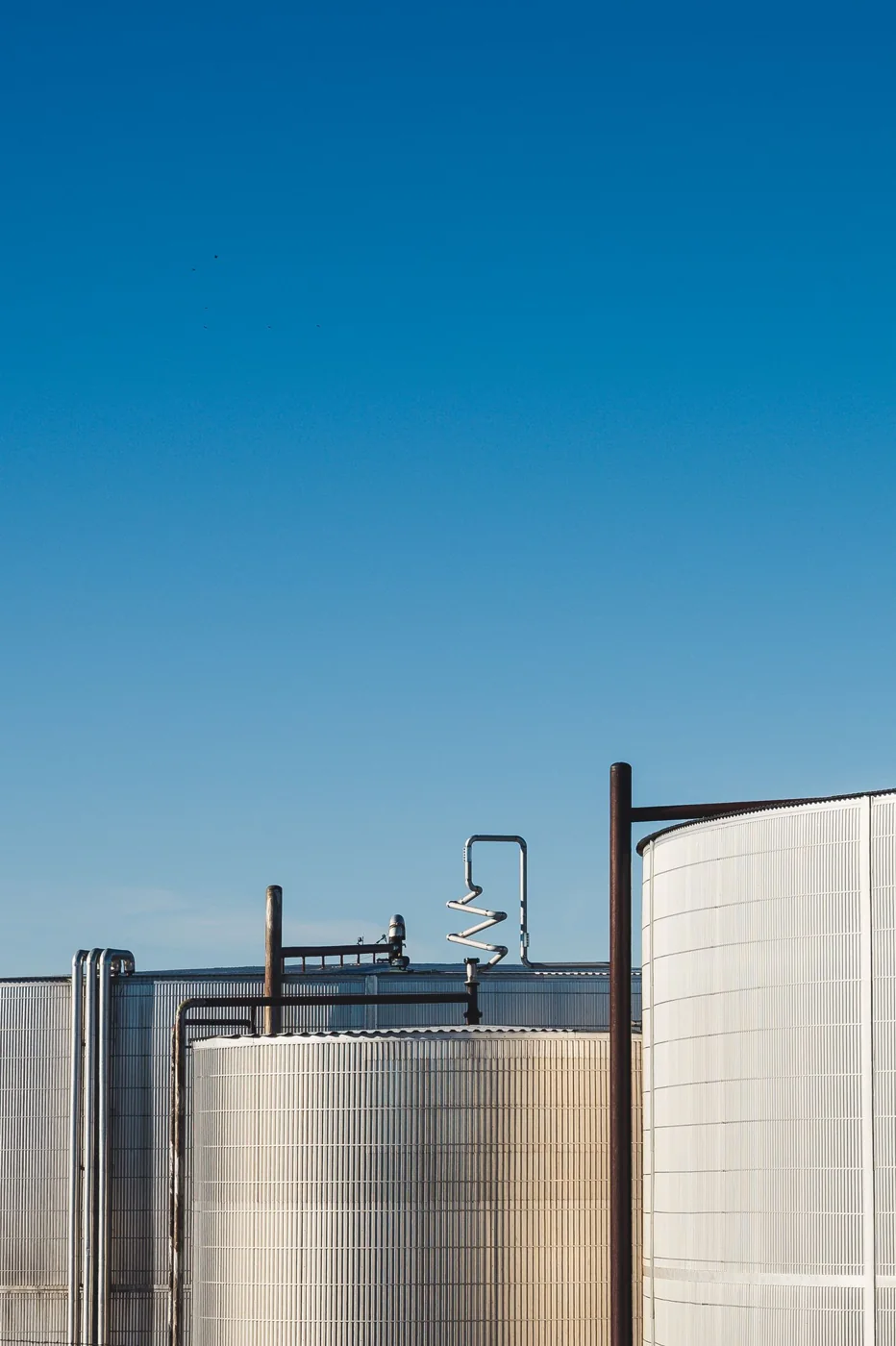 Industrial storage tanks under a clear blue sky